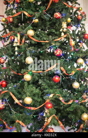 Urlaub, Natur, feiern Konzept. Fichte für Weihnachtsbaum vorbereitet und sorgfältig mit wundervollen Kugeln in verschiedenen Farben, Lichter und roten Bändern geschmückt Stockfoto