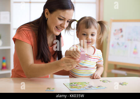 Mutter und Tochter tun spielen puzzle Spielzeug zusammen auf dem Tisch im Kinderzimmer Stockfoto