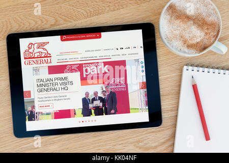 Ein Mann schaut auf die Assicurazioni Generali Website auf seinem iPad tablet device, Schuß gegen einen hölzernen Tisch top Hintergrund (nur redaktionelle Nutzung) Stockfoto