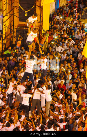 Govindas, Junge, umgeben von Menschenmengen, machen menschliche Pyramiden, um Dahi Handi zu brechen, Pune Stockfoto