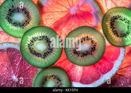 In Scheiben geschnittene rote Grapefruit und Kiwi auf der beleuchteten Fläche Stockfoto