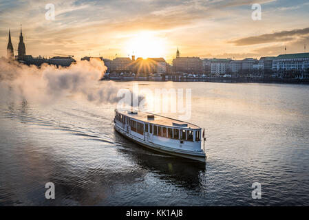 Dampfschiff auf der Alster in Hamburg, Deutschland mit Stadtbild im Hintergrund bei Sonnenuntergang Stockfoto