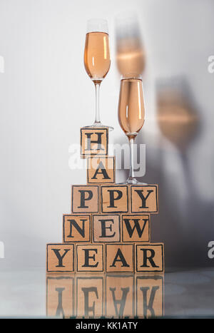 Gläser mit rosigen Champagner eine farbige Schatten und Holzwürfel machen Form der text Frohes neues Jahr aufrecht Stockfoto