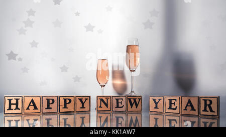 Gläser mit rosigen Champagner eine farbige Schatten und Holzwürfel machen Form der text Frohes neues Jahr mit Sternen Stockfoto