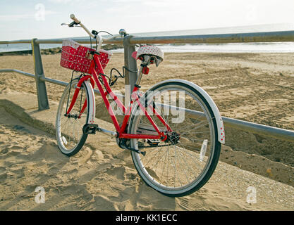 Ein rotes Fahrrad angekettet an Geländer am Strand Stockfoto