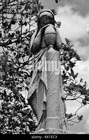 Ein gekleideten Dame liegt in ruhigen und traurigen Kontemplation an einem Grab. Stockfoto