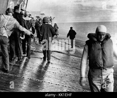 Szene auf dem Flugdeck der USS Yorktown (CV-5) kurz nach war sie von zwei japanischen Lufttorpedos, 4. Juni 1942 getroffen. Männer sind Balancing selbst auf der Liste Deck wie bereiten Sie ihr Schiff zu verlassen. In dieser Ansicht sieht nach der neben der Insel. F4F-4 Wildcat Kämpfer im Hintergrund sichtbar ist die Bekämpfung von Staffel Drei Ebene #6, das von der Stern Brainard T. Macomber während des Morgens geflogen worden waren Angriffe auf die Japanischen träger Flotte. Nicht genügend Kraftstoff verhindert es aus gestartet, Yorktown vom Nachmittag zu verteidigen Flugzeug Angriff torpedieren. Hinweis Schwimmweste getragen von Stockfoto