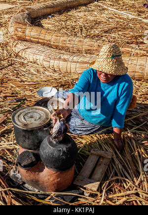 Native uro lady Kochen, schwimmenden Inseln der Uros, Titicacasee, Puno, Peru Stockfoto