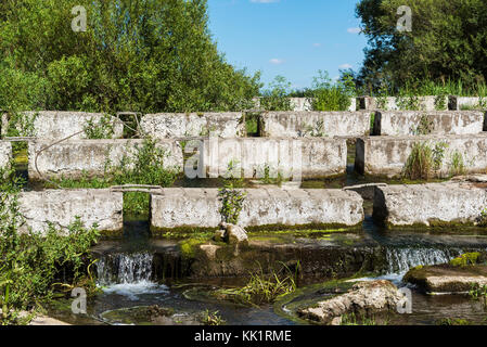 Konkrete Bausteine liegen auf einem kleinen Fluss-dam Stockfoto