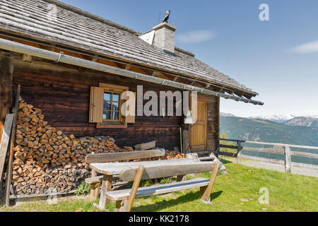 Vorgarten mit holztisch von Hirten Lodge auf einem Hochland Weide mit alpinen Landschaft im westlichen Kärnten, Österreich. Stockfoto