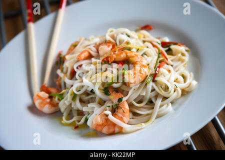 Riesengarnelen mit Knoblauch, Kräutern, Nudeln und Essstäbchen auf weiße Platte. Stockfoto