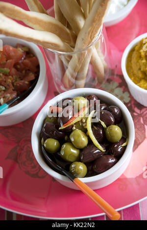 Gemischte Oliven-, Zitronen- und Chili in Weiß Schüssel mit italienischen Grissini zu dienen. Portrait vertikalen Format. Stockfoto