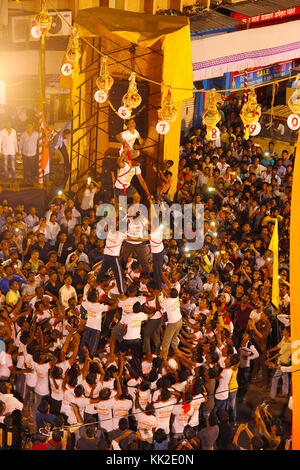 Govindas, Junge, umgeben von Menschenmengen, machen menschliche Pyramiden, um Dahi Handi zu brechen, Pune Stockfoto