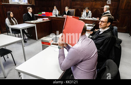 Hamburg, Deutschland. November 2017. Der Angeklagte versteckt sein Gesicht hinter einer Akte, als er neben seinem Anwalt Oliver Klostermann (R) am 29. November 2017 vor dem Amtsgericht Altona in Hamburg sitzt. Ihm wird vorgeworfen, bei Protesten auf dem G20-Gipfel im Juli erneut eine gefährliche Intervention im Luftverkehr und gefährliche körperliche Schäden durchgeführt zu haben. Quelle: Markus Scholz/dpa/Alamy Live News Stockfoto