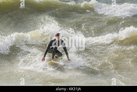 Man surfen auf rauer See einer Welle auf einem Surfbrett, in Großbritannien. Stockfoto
