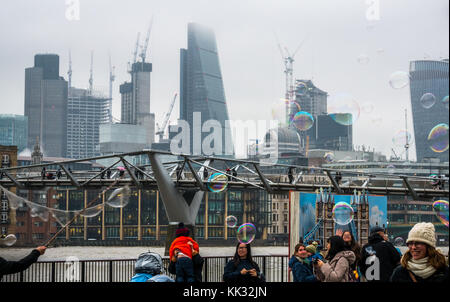 South Bank Themse weg Mann unterhalten Kinder und Leute, die große Blasen, London, England, Großbritannien mit Millennium Bridge, Wolkenkratzer Stockfoto