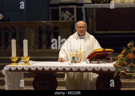 Pavia, Italien. November 11 2017. Ein Priester, der eine heilige Messe im Duomo di Pavia (Kathedrale von Pavia) feiert. Er betet über Brot und Wein auf dem alt Stockfoto