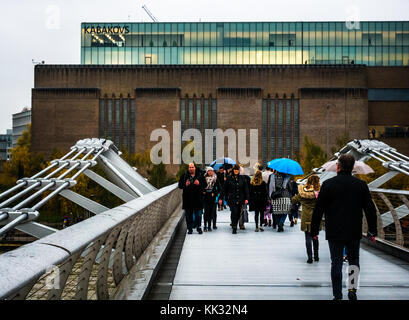 Menschen zu Fuß über die Millennium Bridge an regnerischen Tag mit Sonnenschirmen bis zu Tate Modern Art Galerie mit kabakovs Ausstellung, London, England, Großbritannien Stockfoto