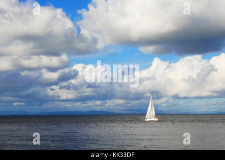 Weiße Yacht mit weissen Segeln Segeln aus dem Fluss Wyre Estuary in Fleetwood und gegen die Fells des Lake District Stockfoto