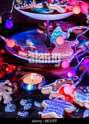 Candle light Tabelle mit Weihnachten Lebkuchen cookies und Weihnachten Girlande und Star Süßigkeiten Dekoration tiered Kuchen stehen auf dem Tisch und brennende Kerzen. Clos Stockfoto