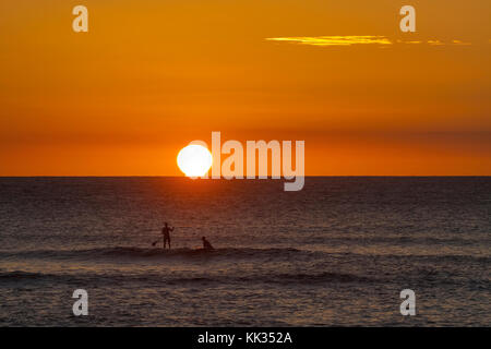 Surfer auf dem Wasser bei Sonnenuntergang am Kaanapali Strand auf Maui. Stockfoto