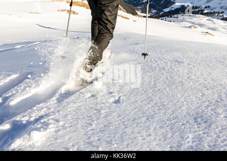 Man bergab laufen durch tiefen Schnee mit snoeshoes und Wanderstöcke. Stockfoto