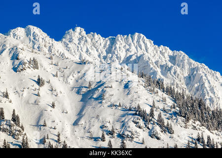 Hohe Berge mit Gipfelkreuz unter tiefen Schnee im Winter. rauhhorn, Allgäu, Bayern in Deutschland. Stockfoto