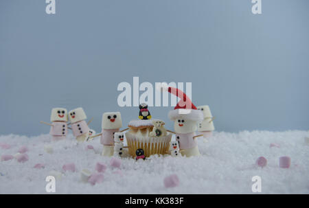 Weihnachten essen Fotografie Bild mit Sahne schwamm Fee Kuchen im Schnee mit Marshmallows, der so glücklich Schneemann und Santa Hut geformte platziert Stockfoto