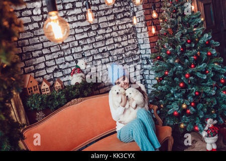 Schöne Frau mit niedlichen Welpen sitzen in der Nähe von Weihnachten Baum. neues Jahr. Stockfoto