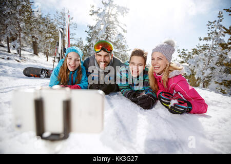 Glückliche Familie zum Skifahren unter selfie beim Liegen auf Schnee Stockfoto