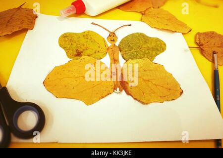 Kinder aus gelben Blätter im Herbst in Form eines Schmetterlings, Kreativität der Kinder, Stockfoto