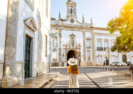 Junge Frau touristische stehend auf dem City Gate Hintergrund in Faro im Süden Portugals Stockfoto