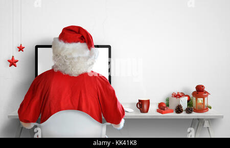 Santa claus Arbeiten am Computer. Weihnachtsschmuck neben mit freien Platz an der Wand für Text. Stockfoto