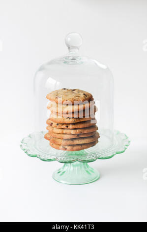 Stapel von frisch gebackenem, hausgemachte, traditionelle amerikanische Chocolate Chip Cookies auf Glas Kuchen stehen auf weißem Hintergrund Stockfoto