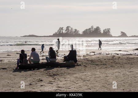 Chesterman Strand in der Nähe von Tofino, BC, Kanada (September 2017) - Familie auf Holzklotzholz sitzen. Stockfoto