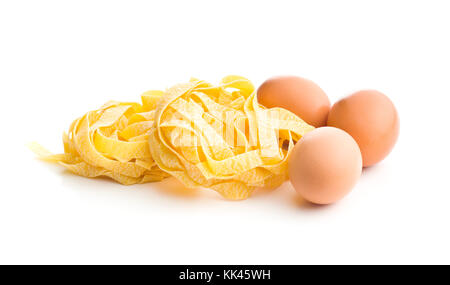 Raw Bandnudeln und drei Eier auf weißem Hintergrund. Stockfoto