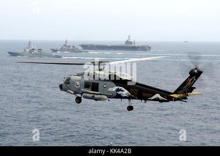 Ein SH-60F Seahawk Helikopter, der den Chargers of Helicopter Anti-U-Boot Squadron HS 14 zugeordnet ist, wird in die Luft gebracht, während der Flugzeugträger USS George Washington CVN 73, der Zerstörer der Japan Maritime Self-Defense Force JS Kirishima DD 174, und der Marine-Zerstörer der Republik Korea ROKS Sejong, die große DDG 991, nehmen an einer trilateralen Veranstaltung Teil, Ostchinesisches Meer, 2012. Bild mit freundlicher Genehmigung von Mass Communication Specialist 1st Class Jennifer A. Villalovos/US Navy. Stockfoto