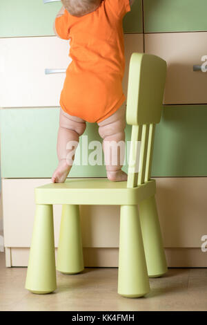 Baby klettern auf Stuhl. Kids Safety Konzeption. Stockfoto