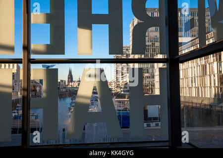 Deutschland, Köln, Rheinauer Hafen, Blick durch die Fenster einer Treppe mit der Aufschrift Rheinauhafen, im Hintergrund der Dom. Stockfoto