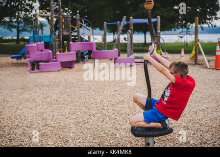 Ein Junge Kind spielt auf Spielgeräte im Sommer Stockfoto