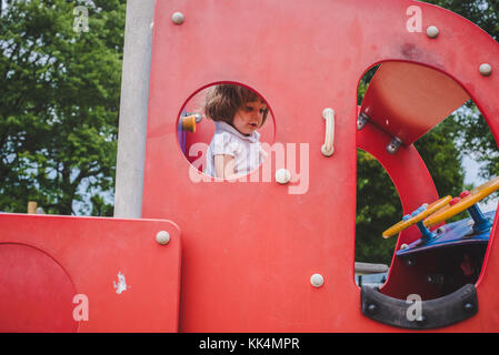 Ein kleines Mädchen klettert an Spielgeräten auf Sommer Tag Stockfoto