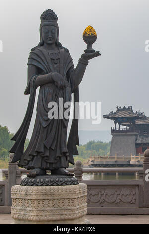 Ein grosser Stein geschnitzte Statue eines buddhistischen diety Holding eine goldene Objekt. Stockfoto