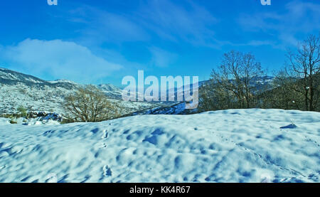 Der Vogel Spuren im Schnee auf dem Hügel mit dem pindosgebirge auf dem Hintergrund, Griechenland. Stockfoto
