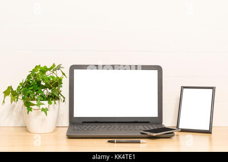Laptop mock up auf Holztisch mit Bilderrahmen, Efeu Pflanze im Topf. Arbeitsplatz in Loft. Innenraum Foto Stockfoto