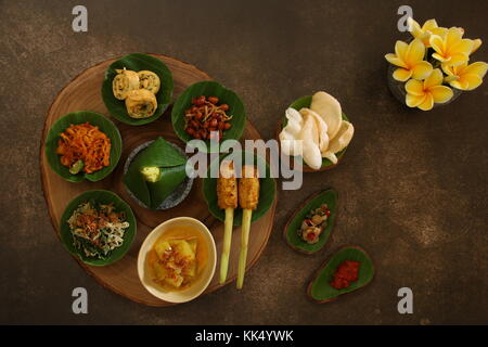 Balinesische essen Sampler. Verschiedene balinesische Gerichte in kleinen Portionen auf mini Stein Mörser dann auf Holzbrett angeordnet. Stockfoto