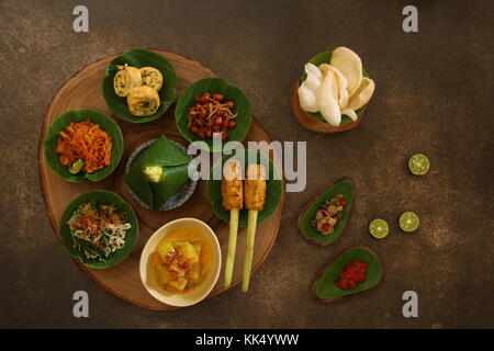 Balinesische essen Sampler. Verschiedene balinesische Gerichte in kleinen Portionen auf mini Stein Mörser dann auf Holzbrett angeordnet. Stockfoto