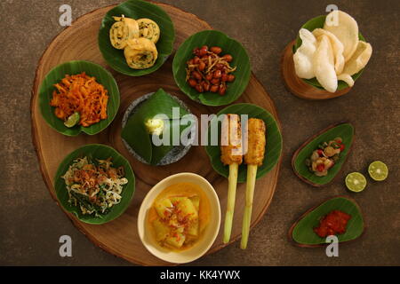 Balinesische Essen Sampler. Verschiedene balinesische Gerichte in kleinen Portionen auf mini Stein Mörser dann auf Holzbrett angeordnet. Stockfoto