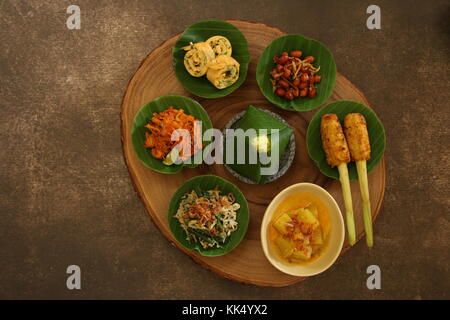 Balinesische Essen Sampler. Verschiedene balinesische Gerichte in kleinen Portionen auf mini Stein Mörser dann auf Holzbrett angeordnet. Stockfoto