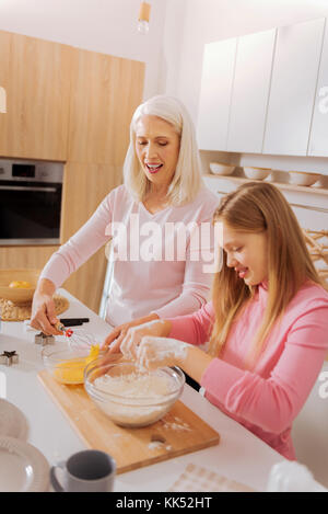 Spaß Unterhaltung. Happy positive Großmutter und Enkelin stehen zusammen in der Küche und kochen und dabei Spaß haben Stockfoto