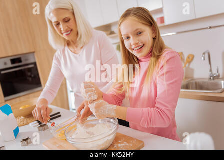 Lustige Aktivität. positive Schönes fröhliches Mädchen lächelnd und suchen Sie mit Spaß in der Küche Stockfoto